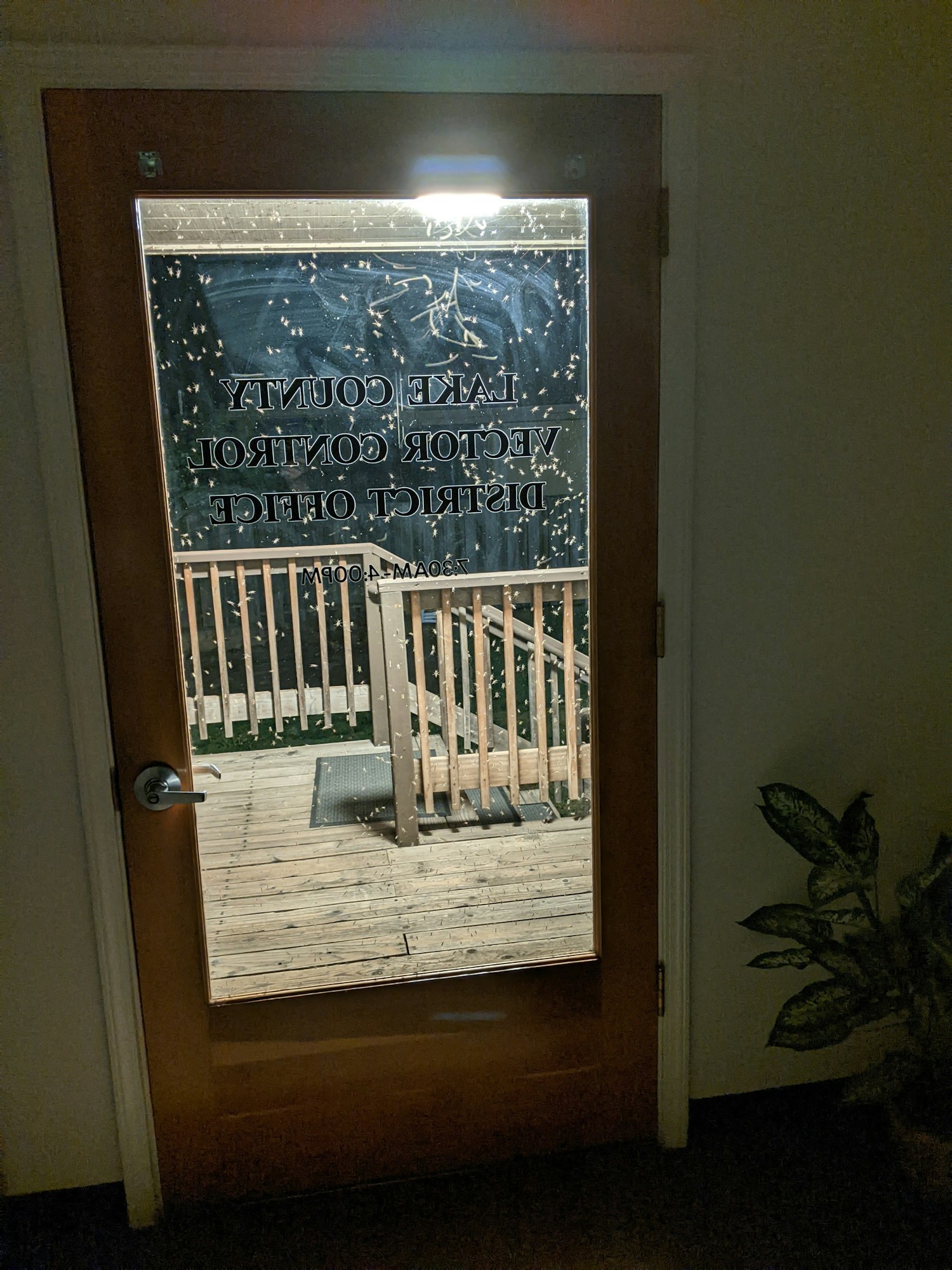 A door with a glass panel shows the words "Lake County Voter Control District Office" and a wooden deck outside.