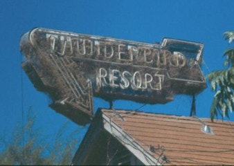 A weathered neon sign reads "Thunderbird Resort" against a clear blue sky.
