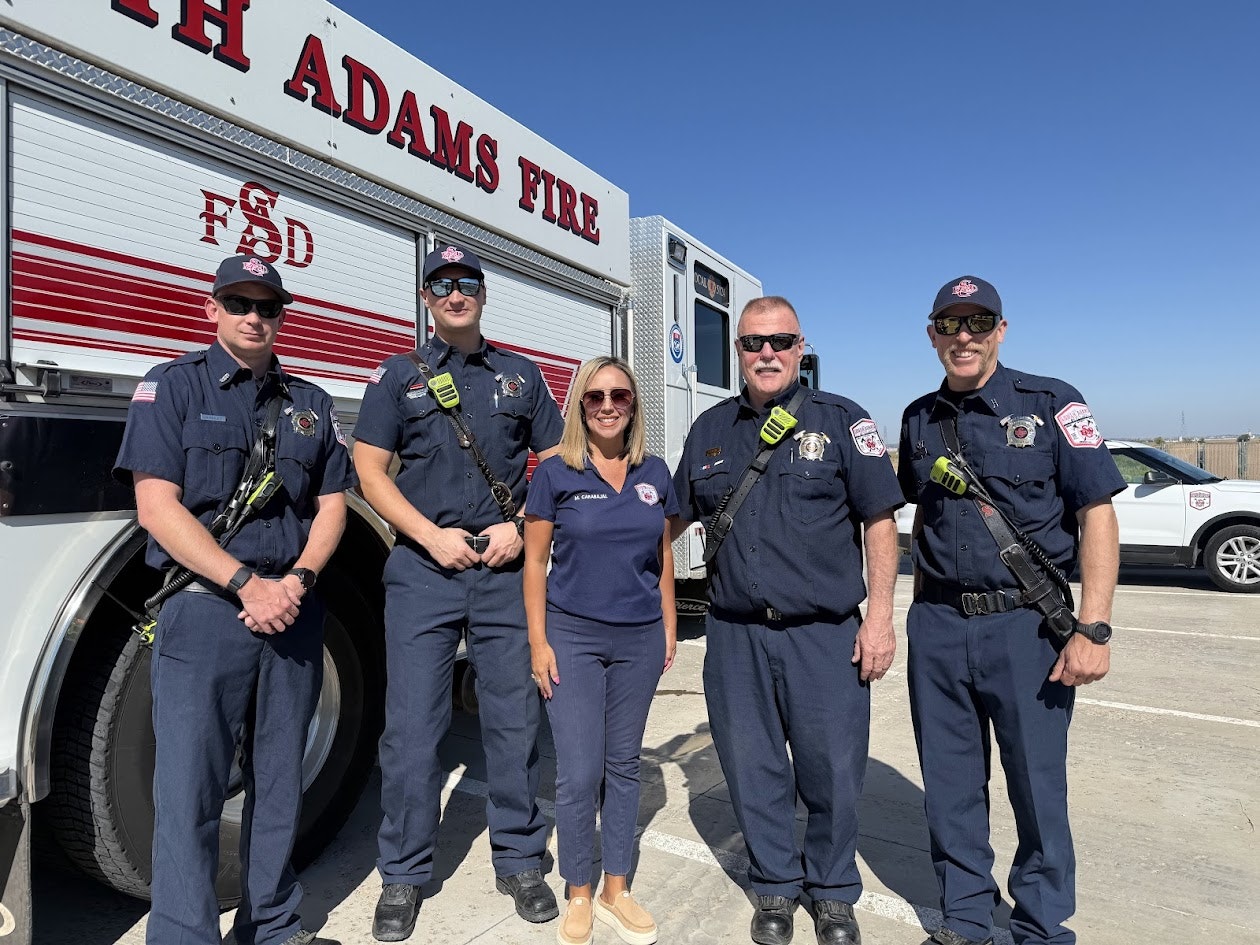 Four firefighters and one woman stand in front of a fire truck from South Adams Fire Department.