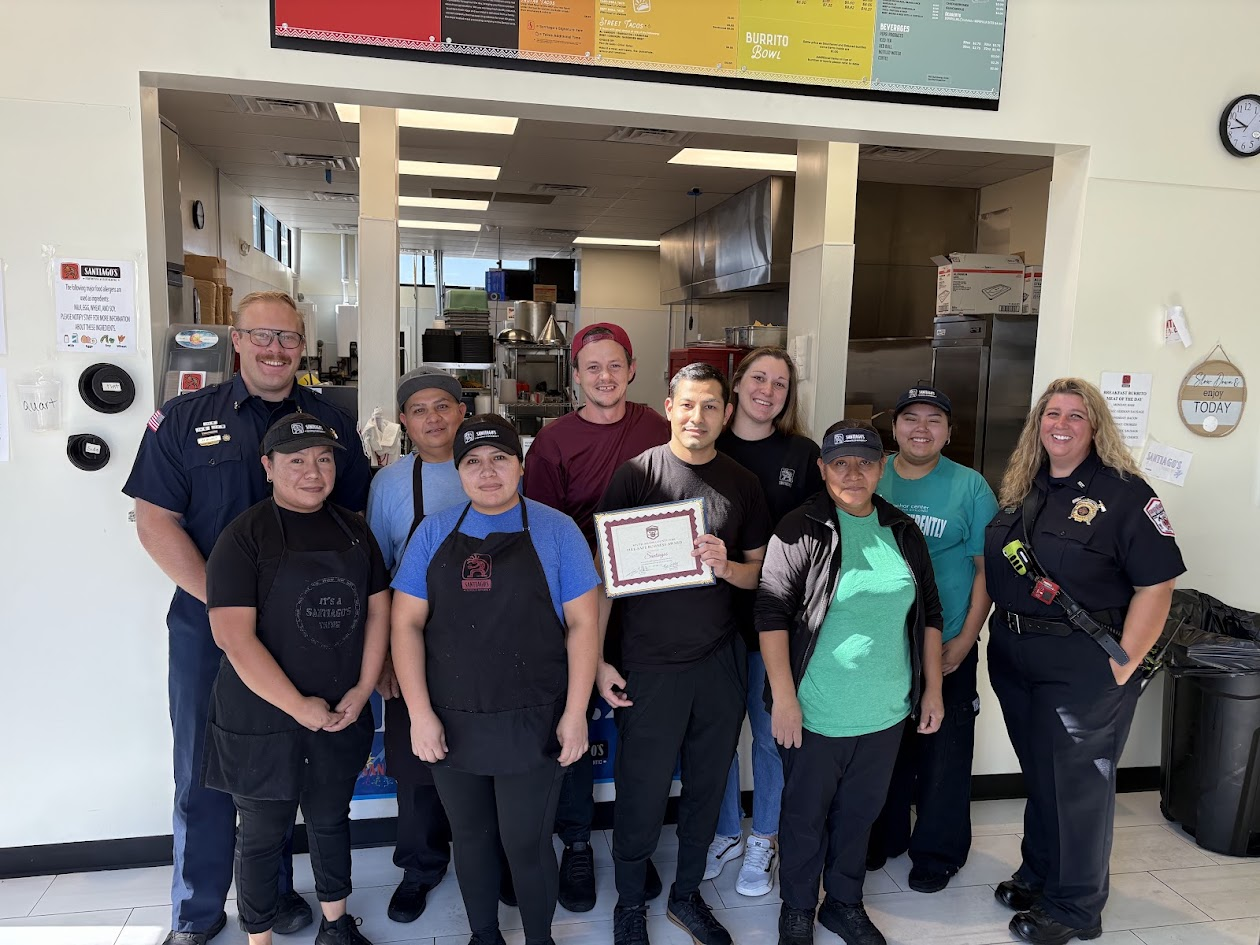 A group photo featuring restaurant staff and officials, holding a certificate in a dining establishment.
