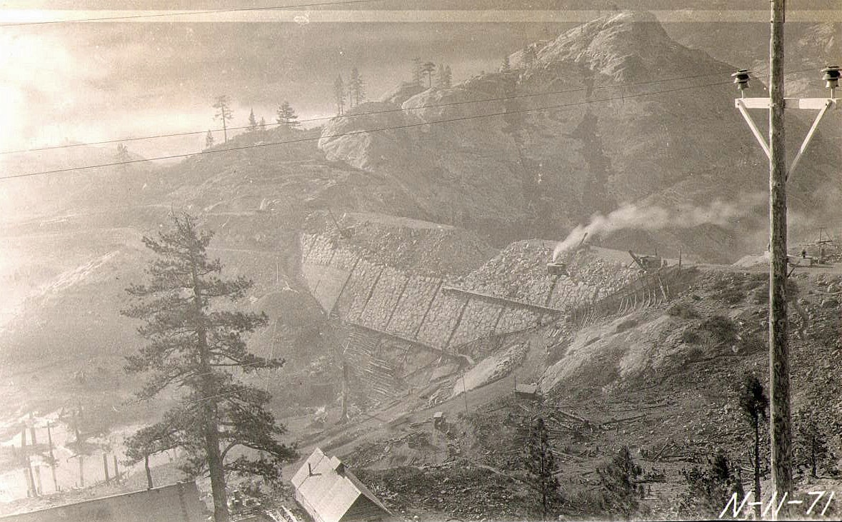 An old black-and-white photo showing a mountainous landscape with mining activities, machinery, and trees.