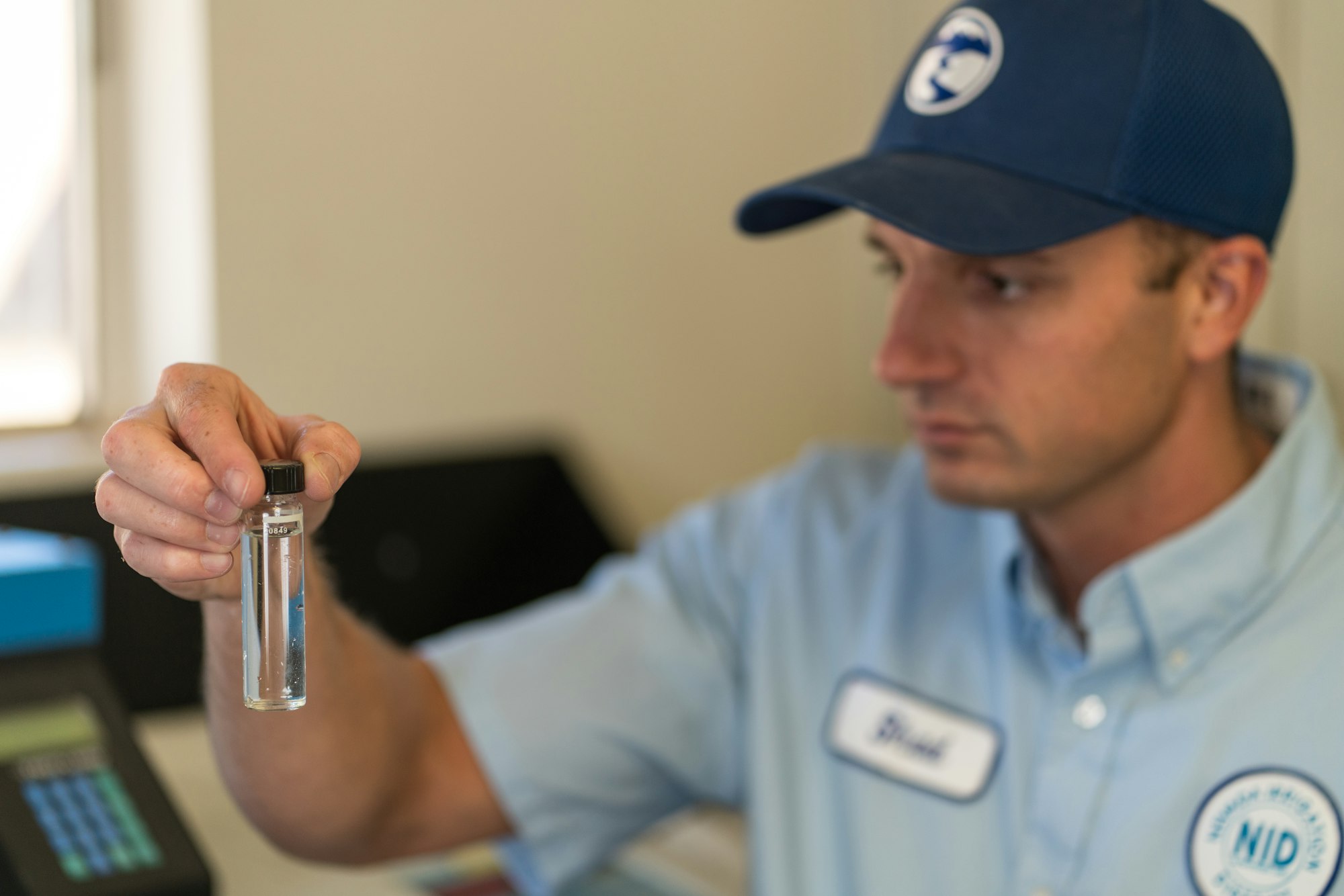 A person is holding a small test tube filled with liquid, possibly for analysis or inspection in a lab setting.