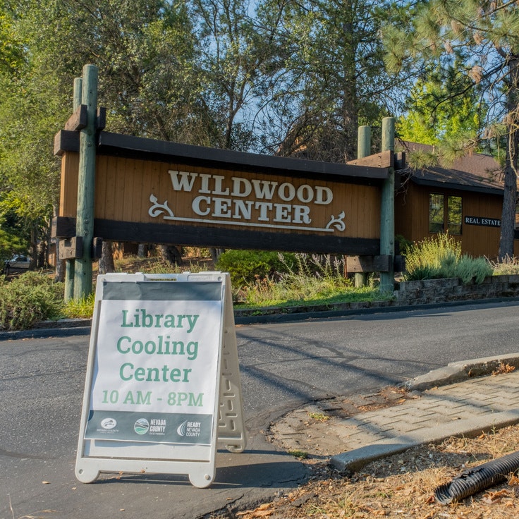 Sign for Wildwood Center and a sandwich board promoting a library cooling center open from 10 AM to 8 PM.