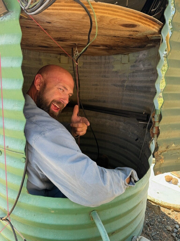 Man in a corrugated metal enclosure giving a thumbs-up.