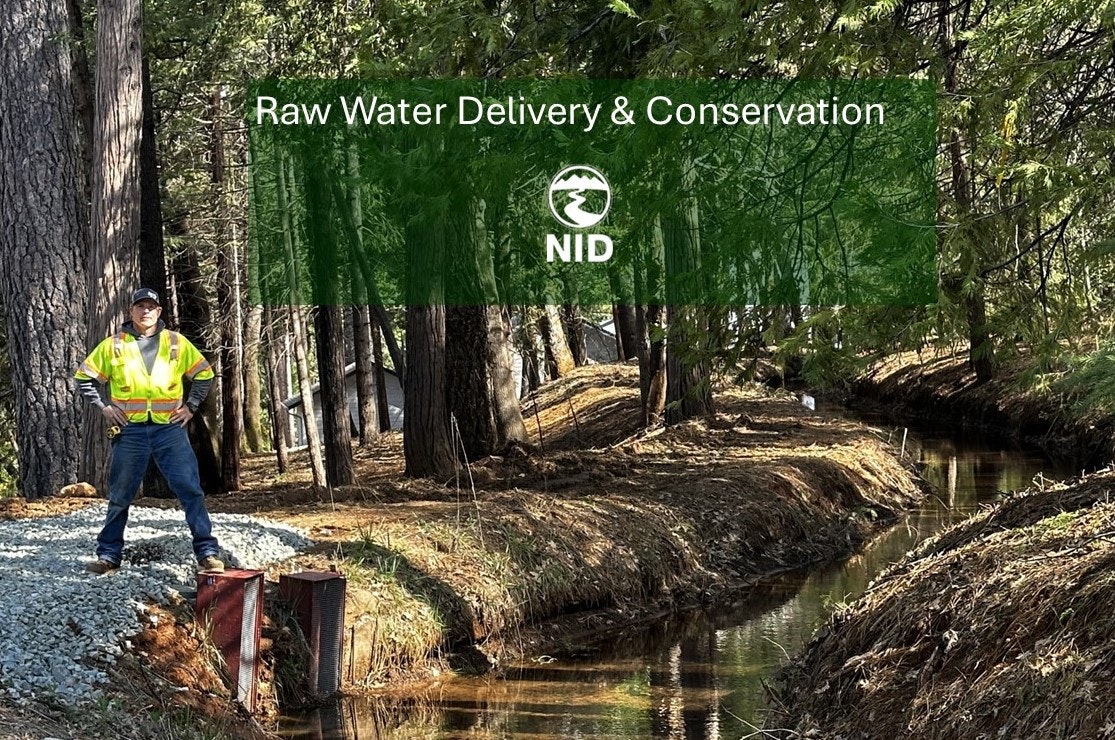 A person in a safety vest stands by a forest creek with a sign for water delivery & conservation.