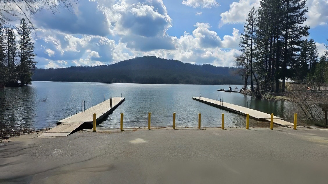 A serene lake scene features wooden docks, trees, and a distant mountain under a cloudy sky. Perfect for relaxation and recreation.