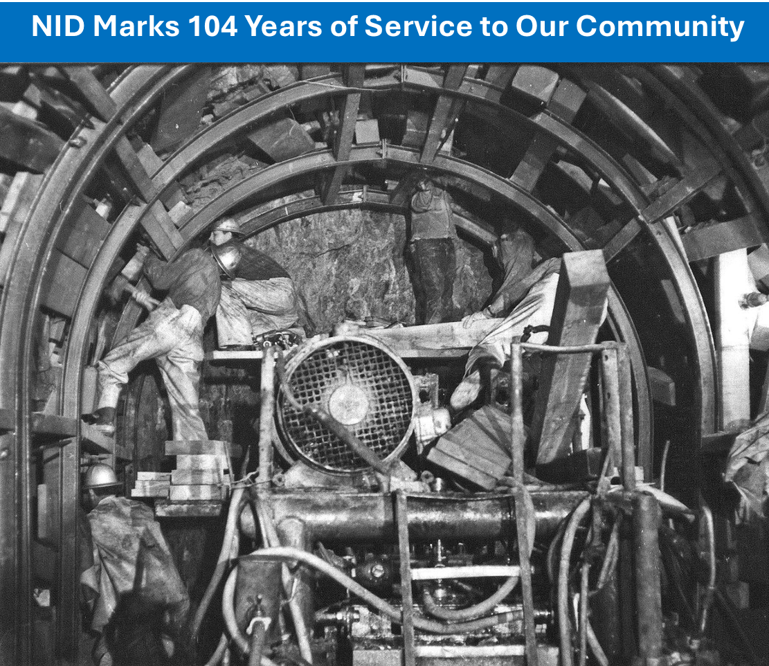 Workers constructing a tunnel using machinery, celebrating 104 years of community service.