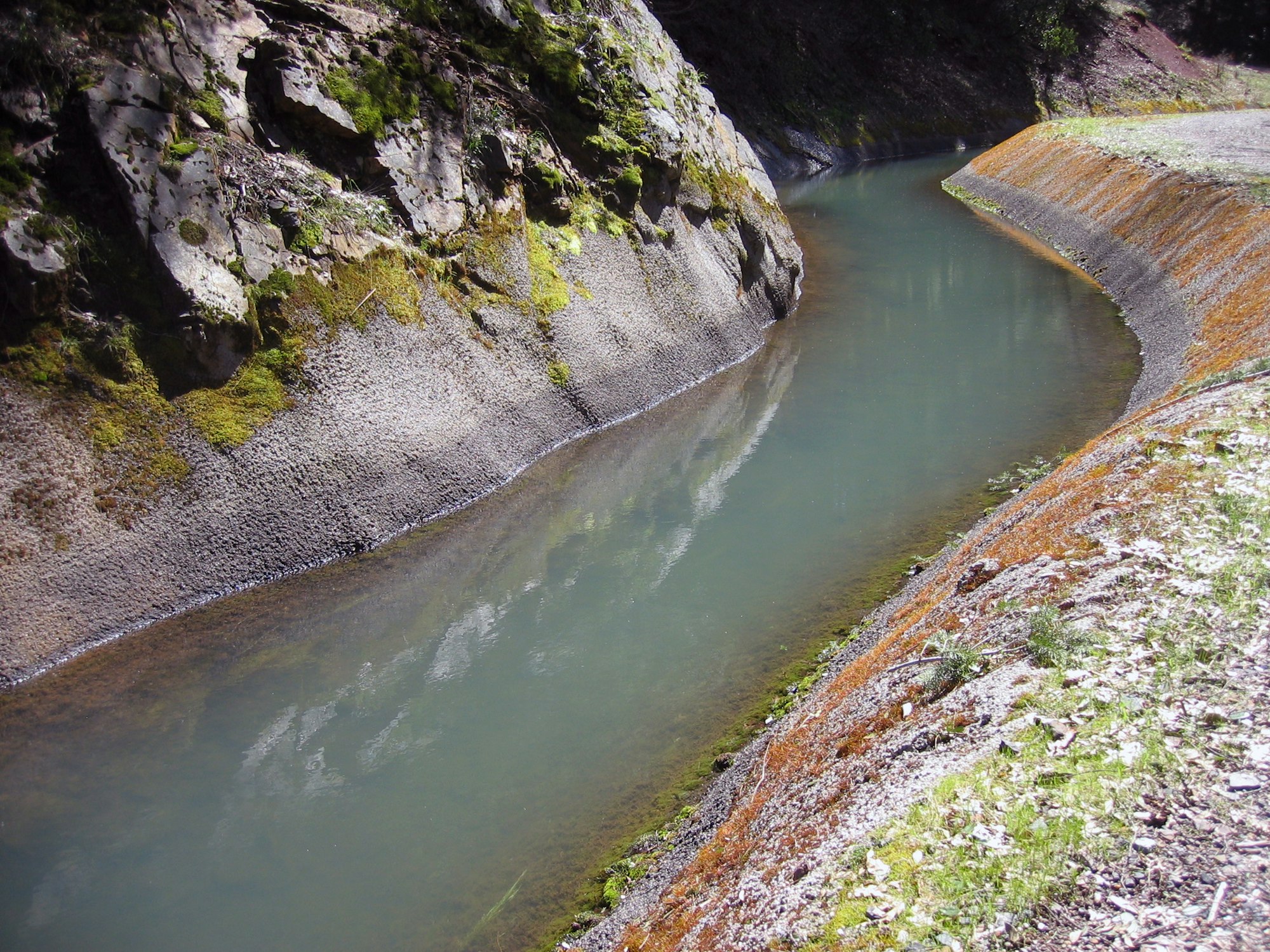 A serene river curving through a rocky landscape with moss and sparse vegetation.