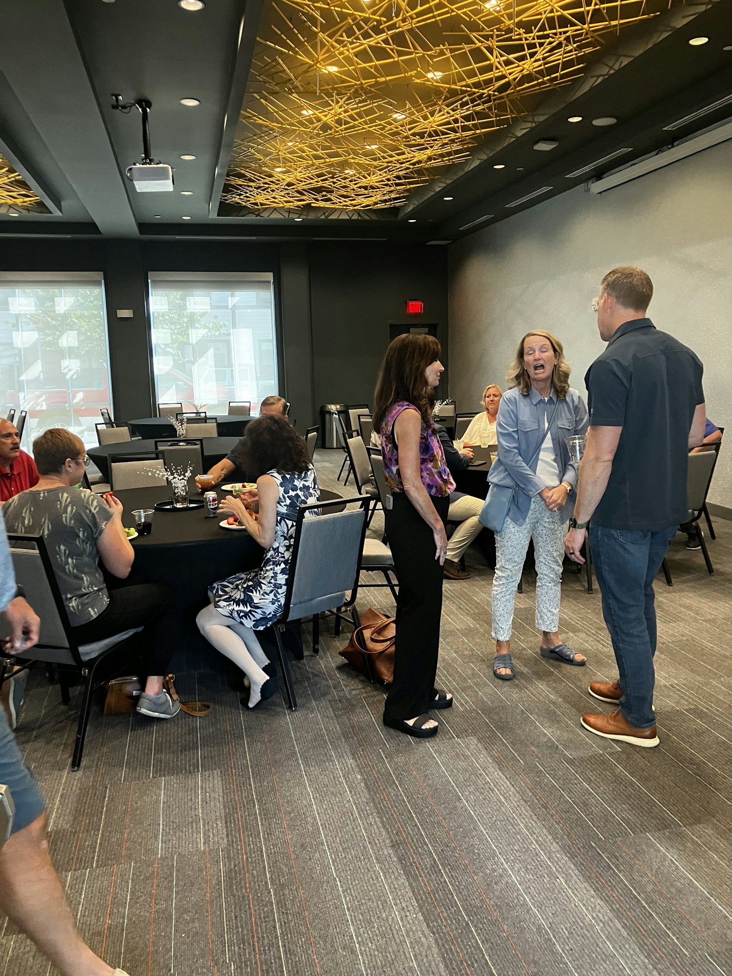 A group of people socializing in a room with modern lighting and decor.