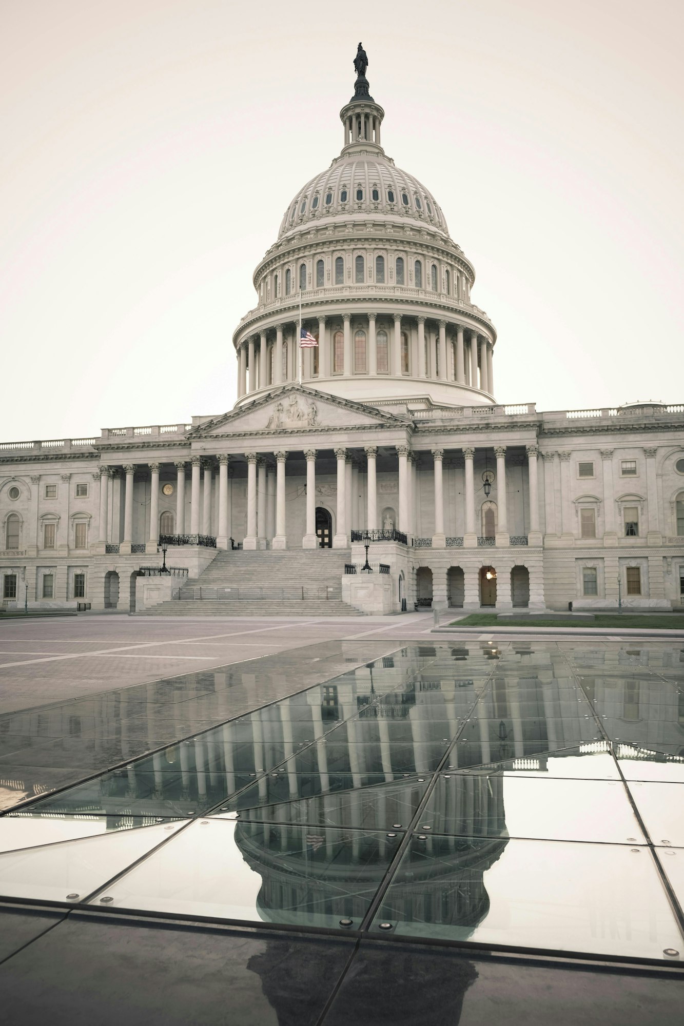 The United States Capitol with a reflection on a glass surface in the foreground.