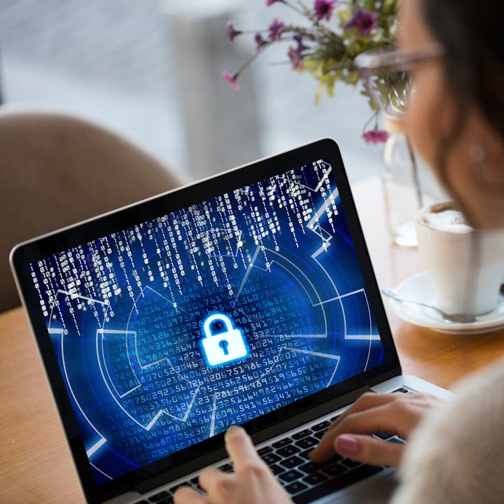 A person using a laptop displaying a digital padlock and binary code, symbolizing cybersecurity.