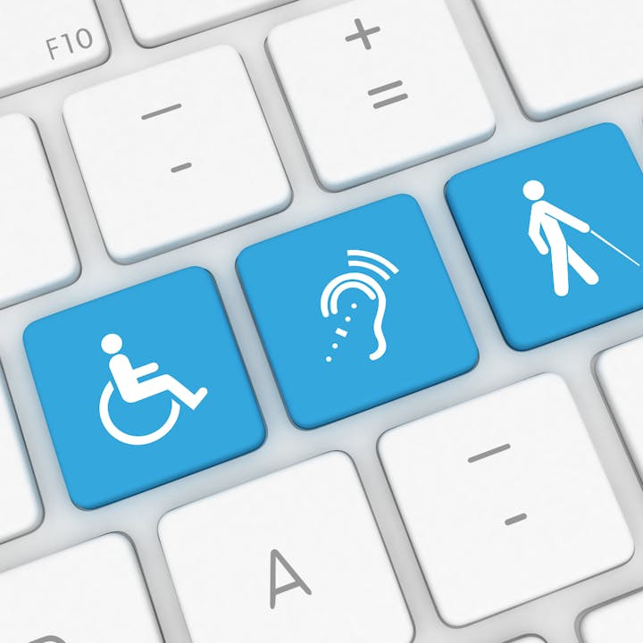 Keyboard with blue keys showing accessibility symbols: wheelchair, hearing, and visual impairment.