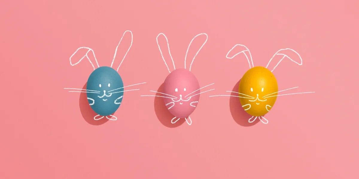 Three colored eggs with bunny faces and ears drawn on a pink background.