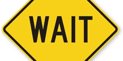 A yellow diamond-shaped sign with the word "WAIT" in bold black letters.