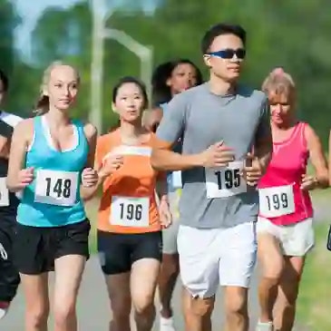 A group of people running a race outdoors, wearing numbered bibs.