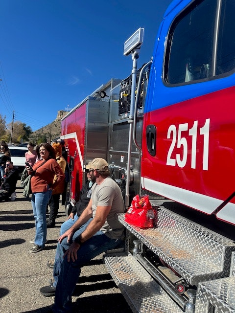 A red fire truck with people gathered around on a sunny day, rotated 90 degrees to the left.