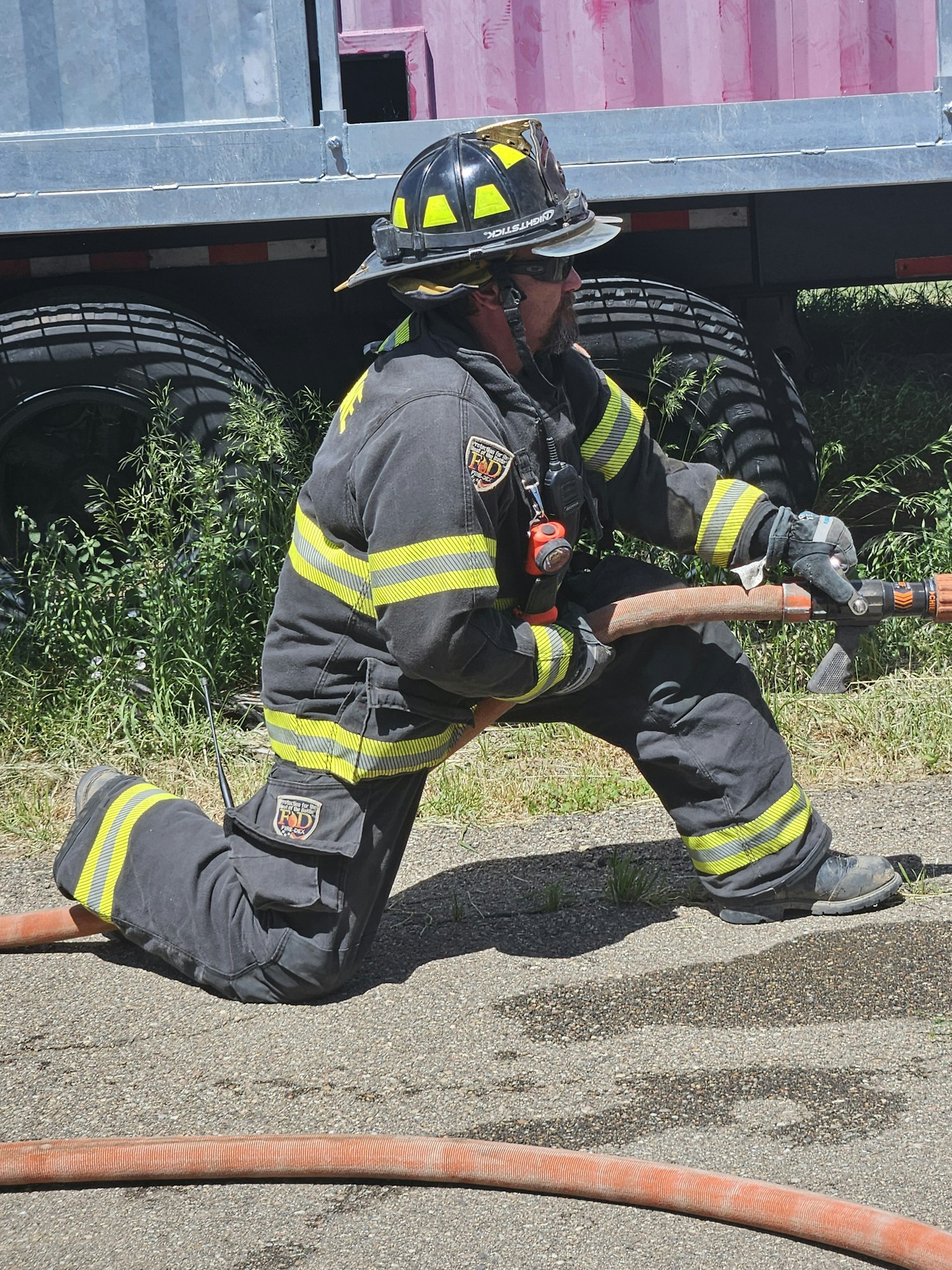 A firefighter handling equipment, possibly during training or an emergency response. Image is rotated 90 degrees clockwise.
