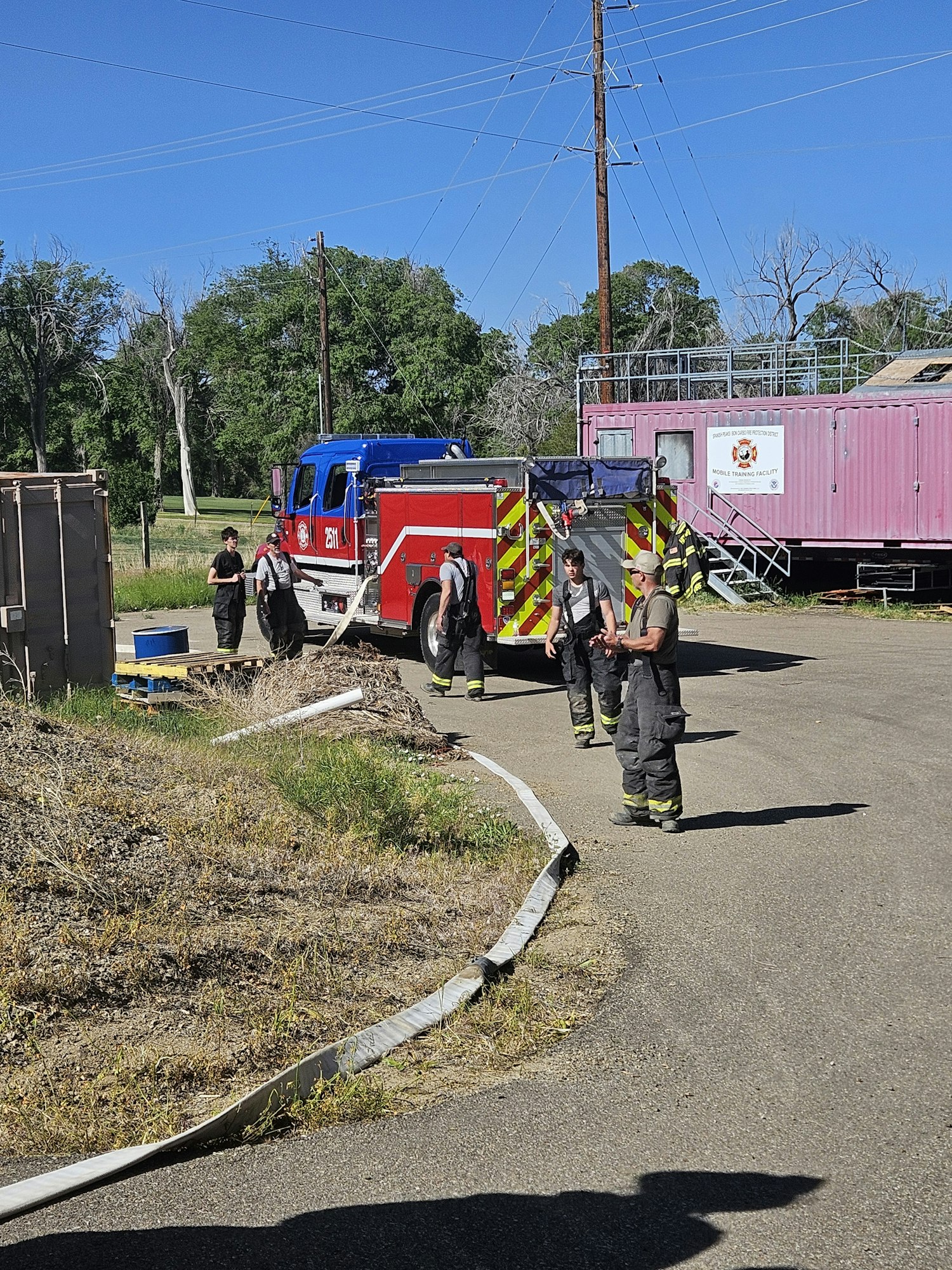 May contain: person, fire truck, transportation, truck, vehicle, clothing, footwear, shoe, helmet, road, hat, and box