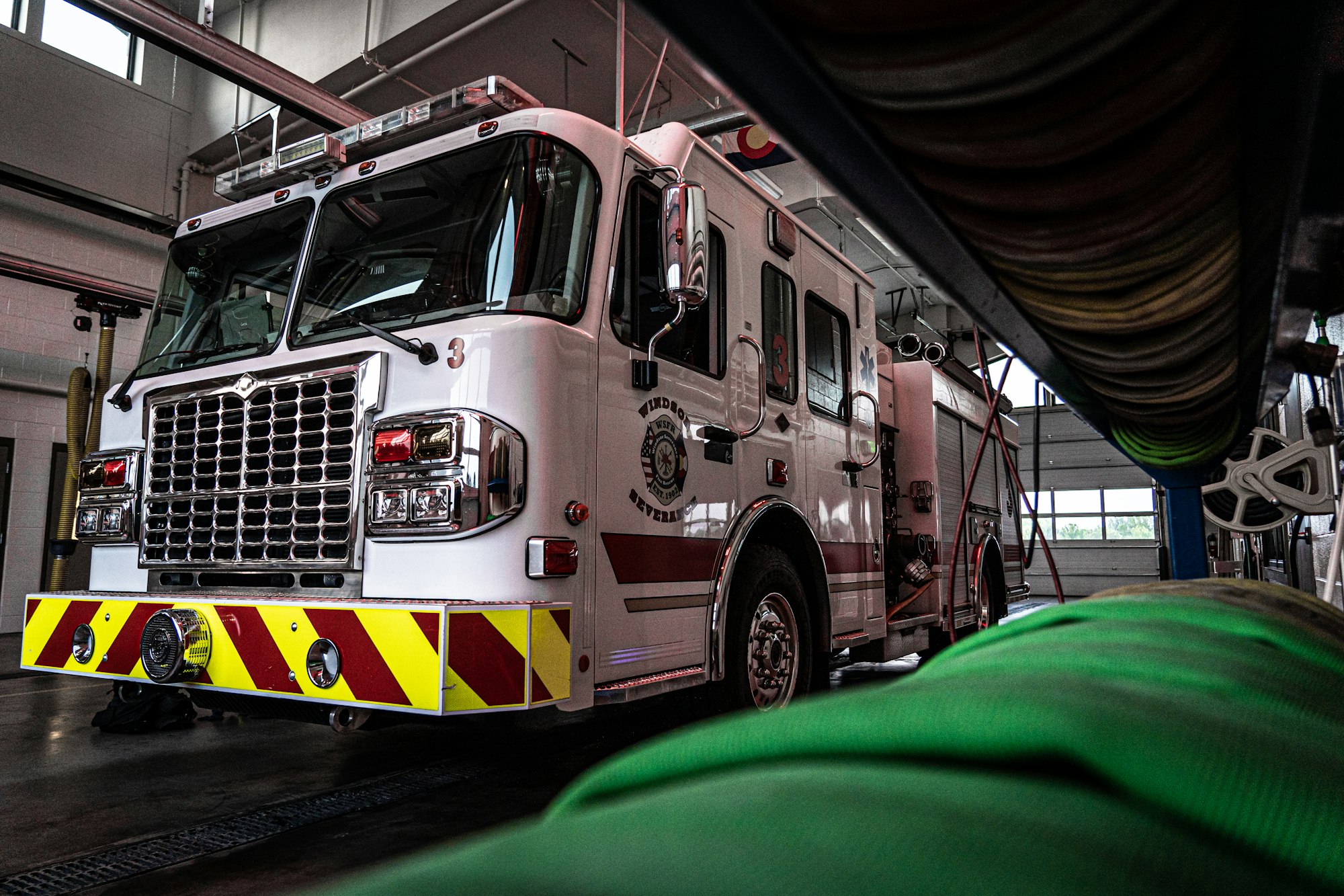 A fire truck parked inside a fire station, with equipment visible in the background.