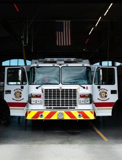 Fire truck parked in a station, American flag hanging above.