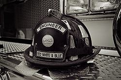 A firefighter's helmet with "ENGINEER" written on it, resting on diamond plate metal.