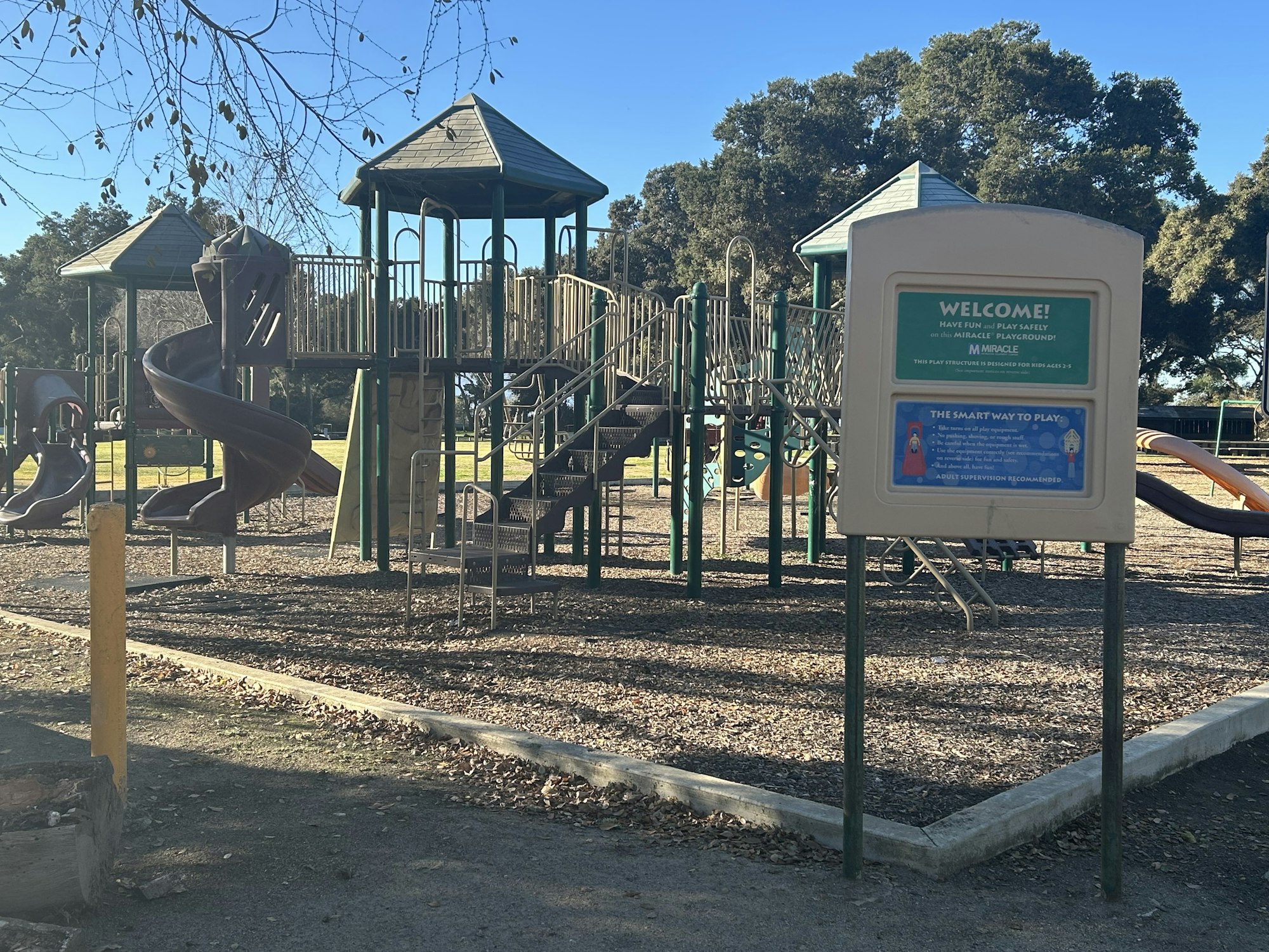Playground with a slide, climbing structures, and a welcome sign.