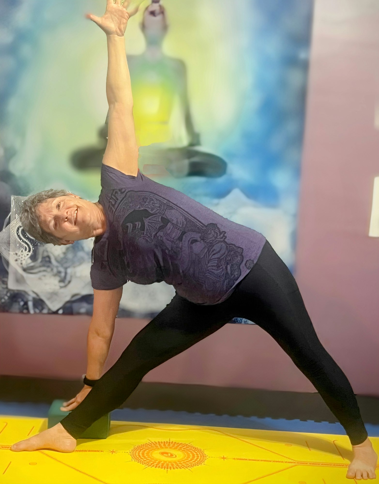 A person practicing yoga on a mat in a side bend pose, in front of a colorful mural.