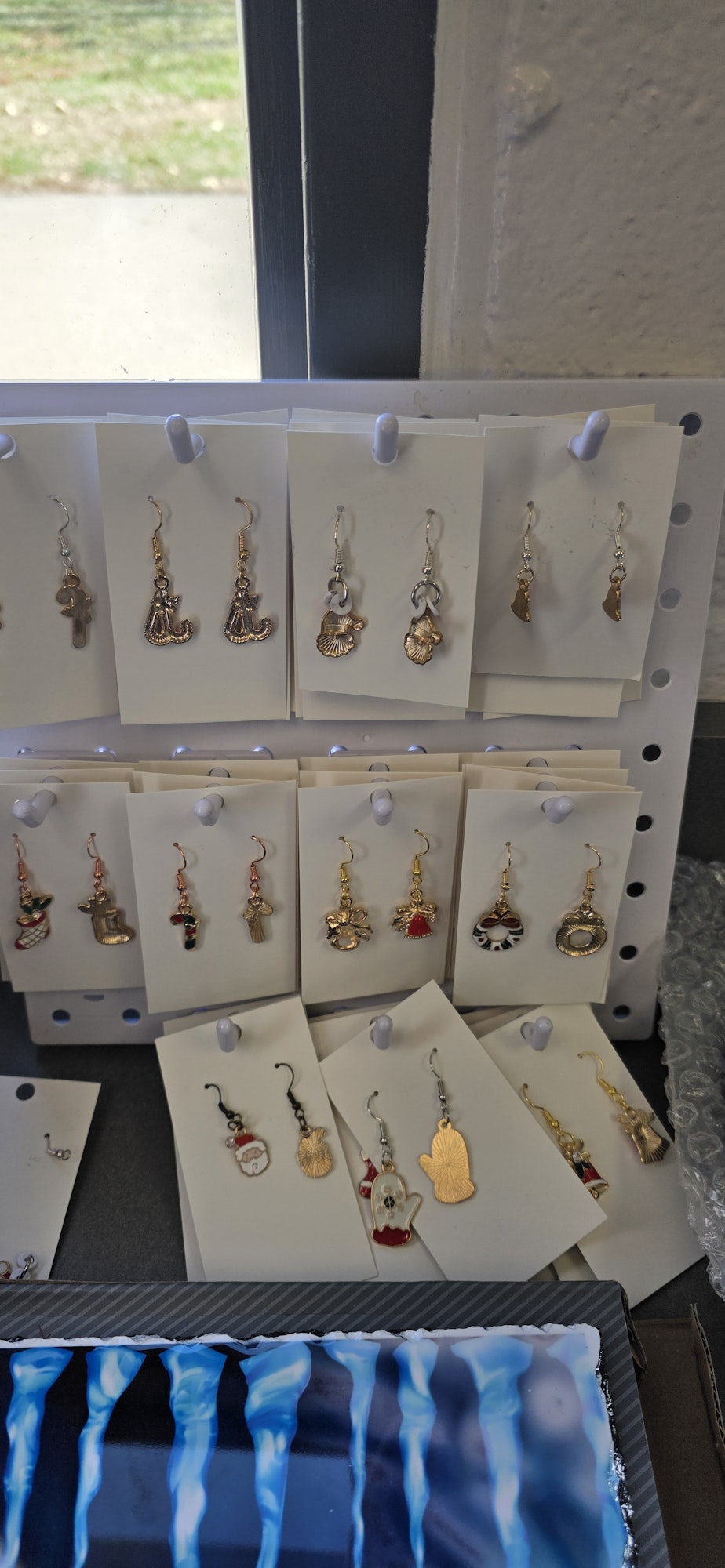 A display of various decorative earrings on white cards, organized on a rack.