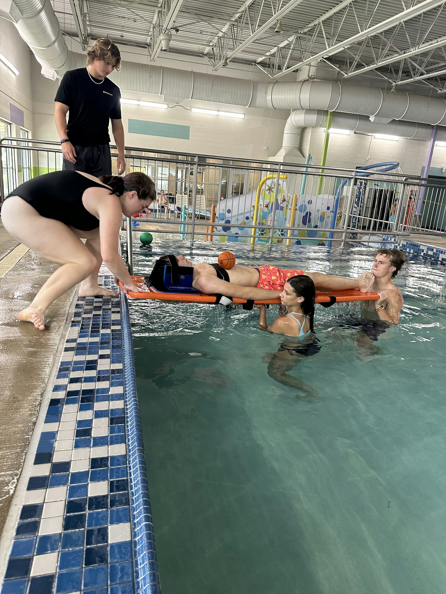 Lifeguards practings water rescues removing a guest from the water on a backboard