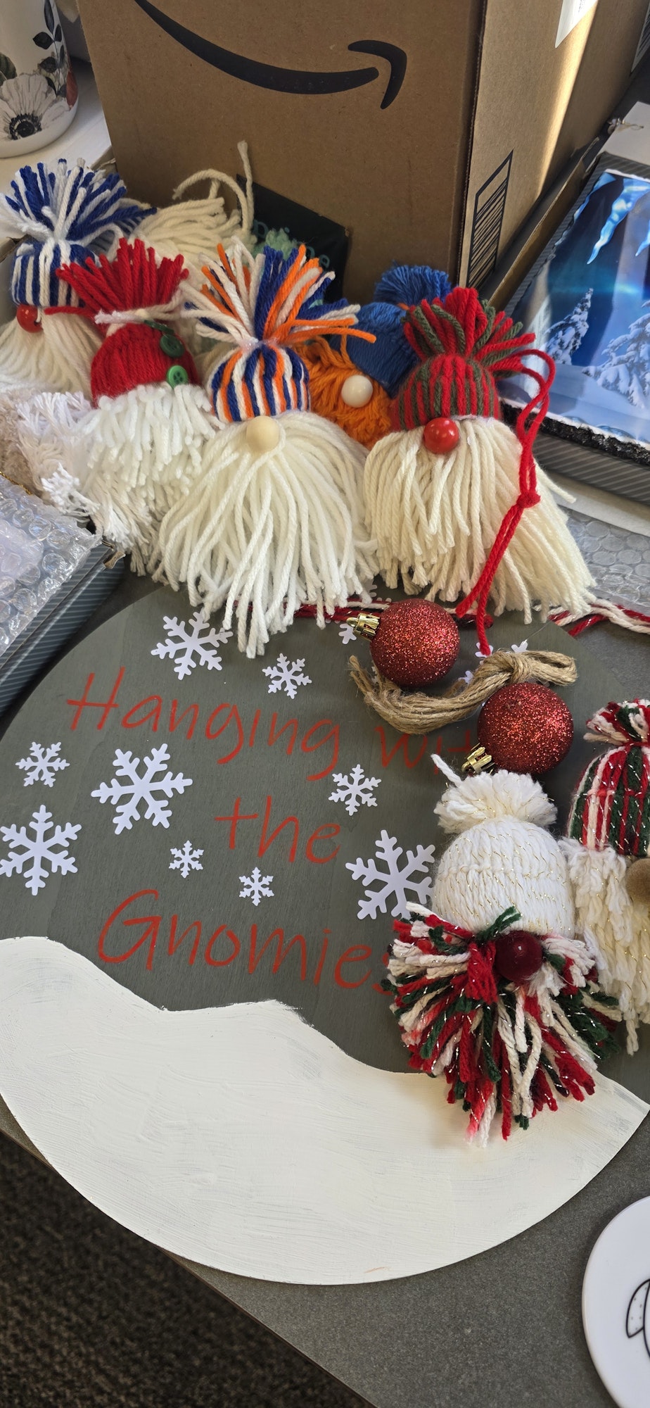 Crafted yarn gnomes and Christmas decorations with a sign that reads "Hanging with the Gnomies," surrounded by snowflakes.