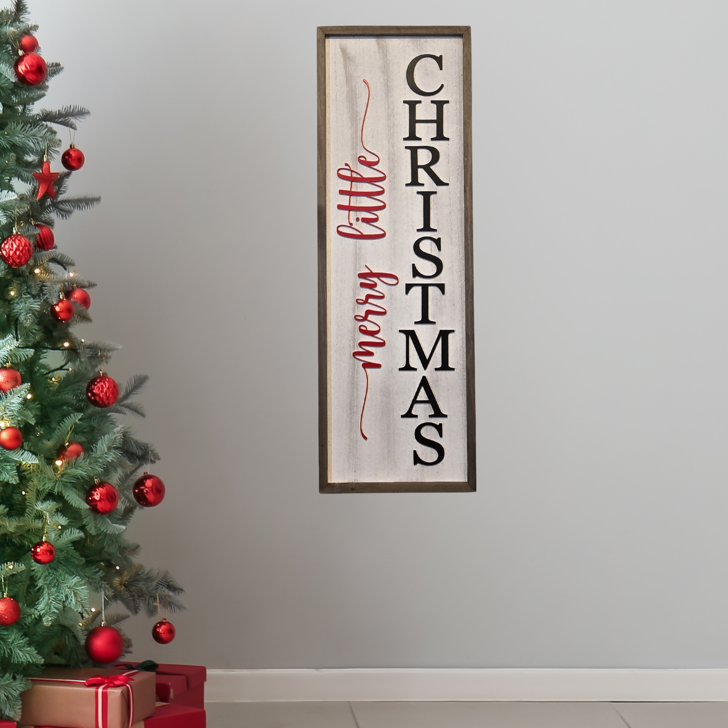 A festive sign saying "Merry Little Christmas" beside a decorated Christmas tree with red ornaments.