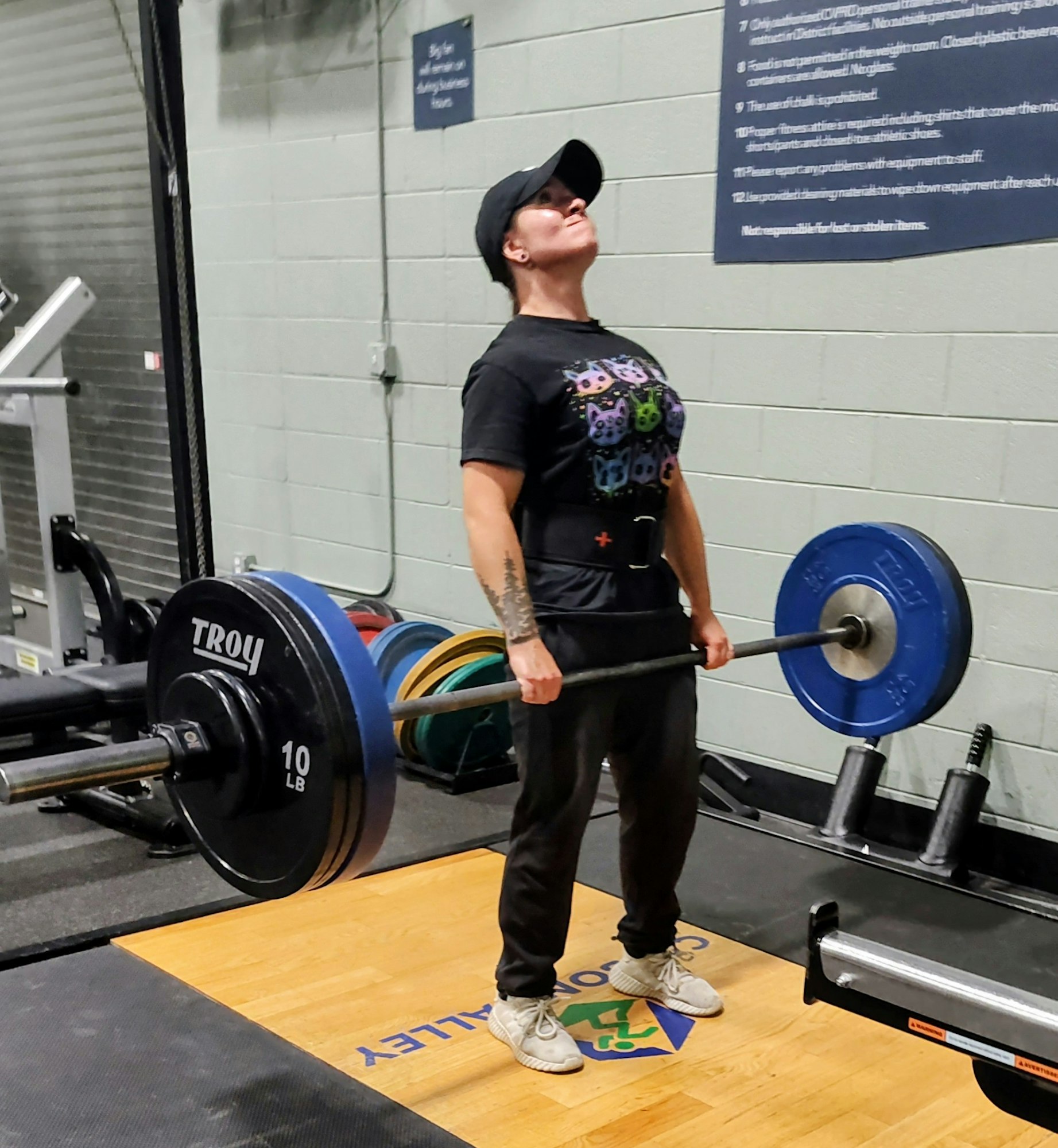 A person is lifting a barbell loaded with weights at a gym, focusing intently on their form.