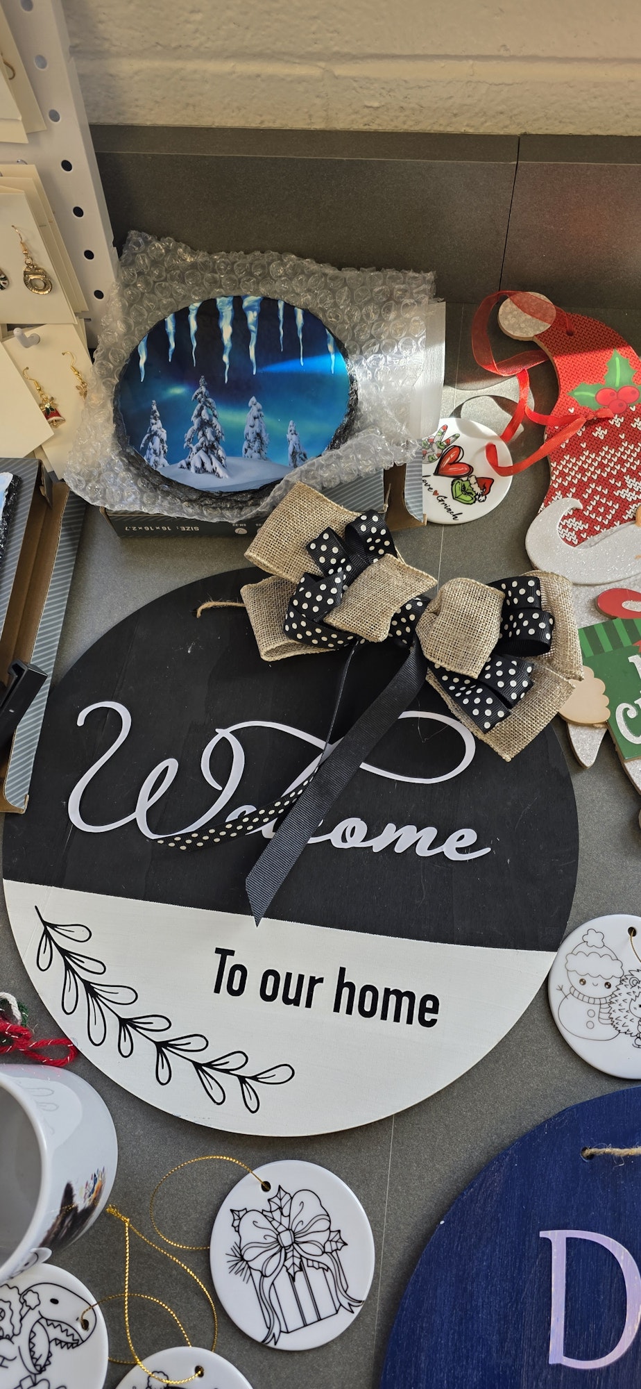 A collection of decorative items, including a "Welcome To our home" sign with a bow, ornaments, and a circular winter scene.