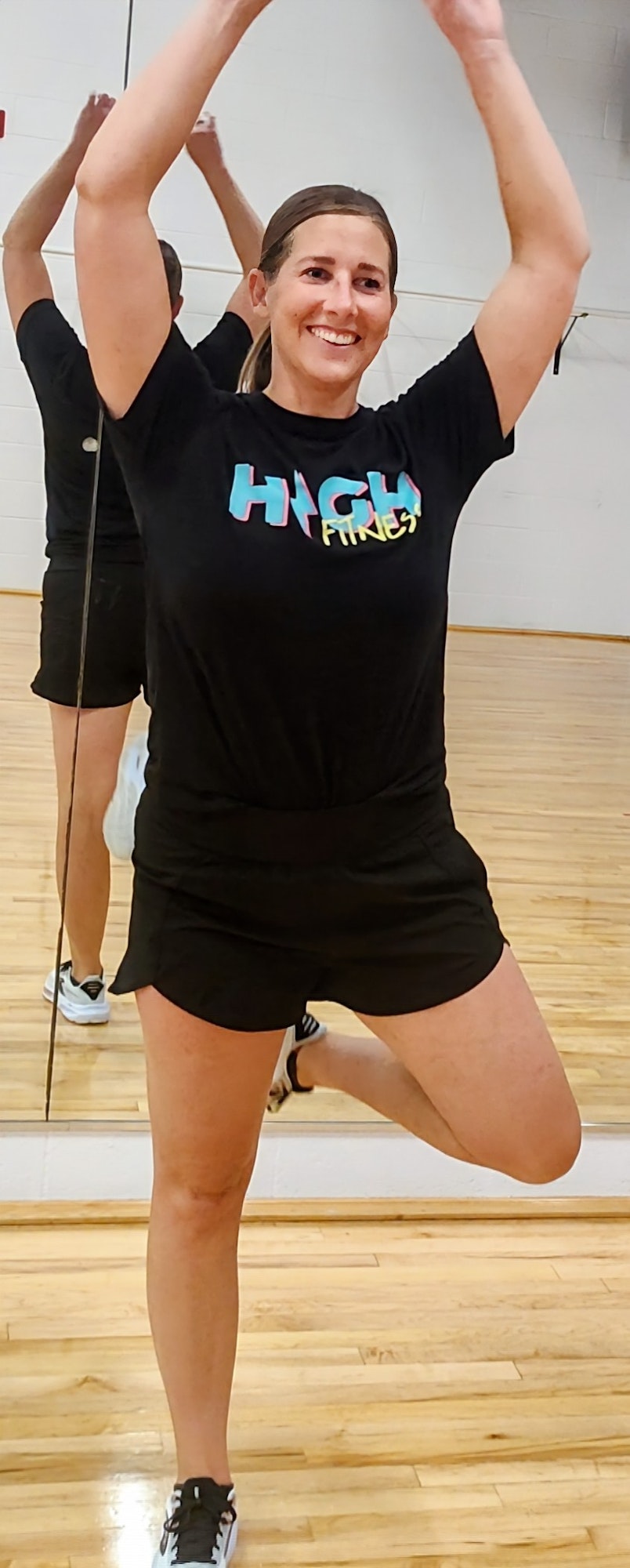 A smiling person in a fitness outfit poses during a workout, highlighting a lively and energetic atmosphere.