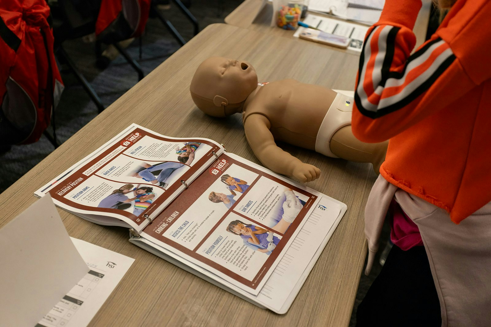A training setup with a baby mannequin and a manual for first aid techniques.