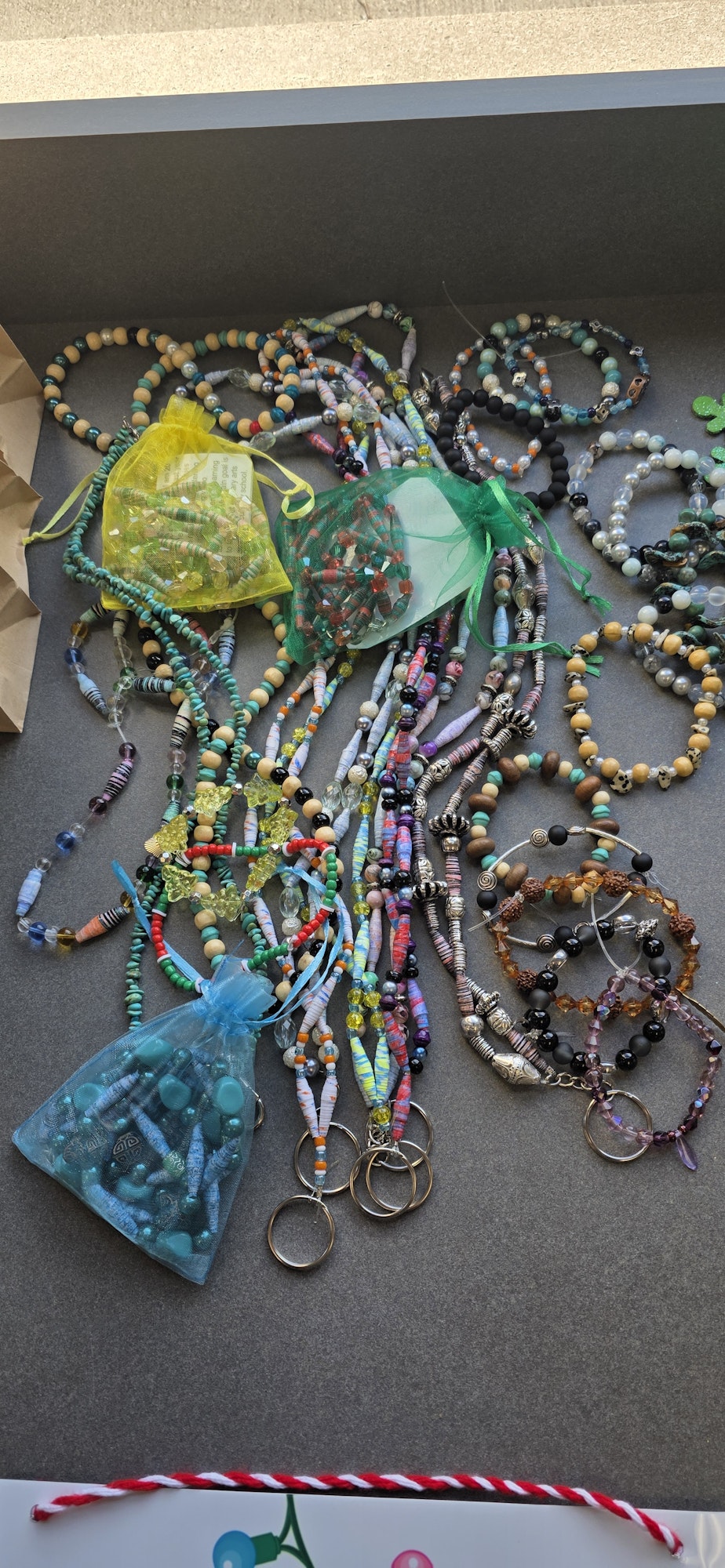 Colorful handmade bead bracelets and necklaces with organza bags on a table.
