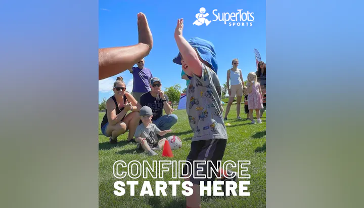 A child celebrates during a sports event, engaging with adults and peers, highlighting fun and confidence in a playful environment.