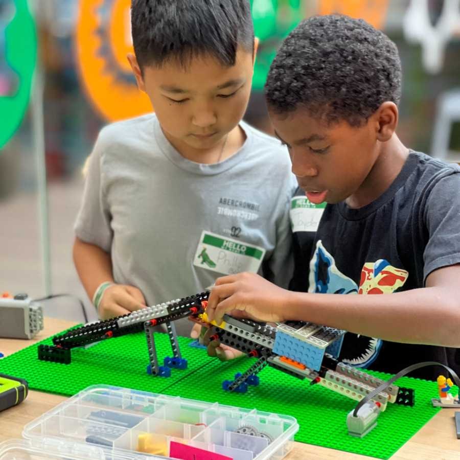 Two kids are engaged in building a LEGO structure, with concentration and teamwork.