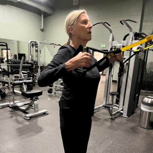 A person exercising with suspension straps in a gym.