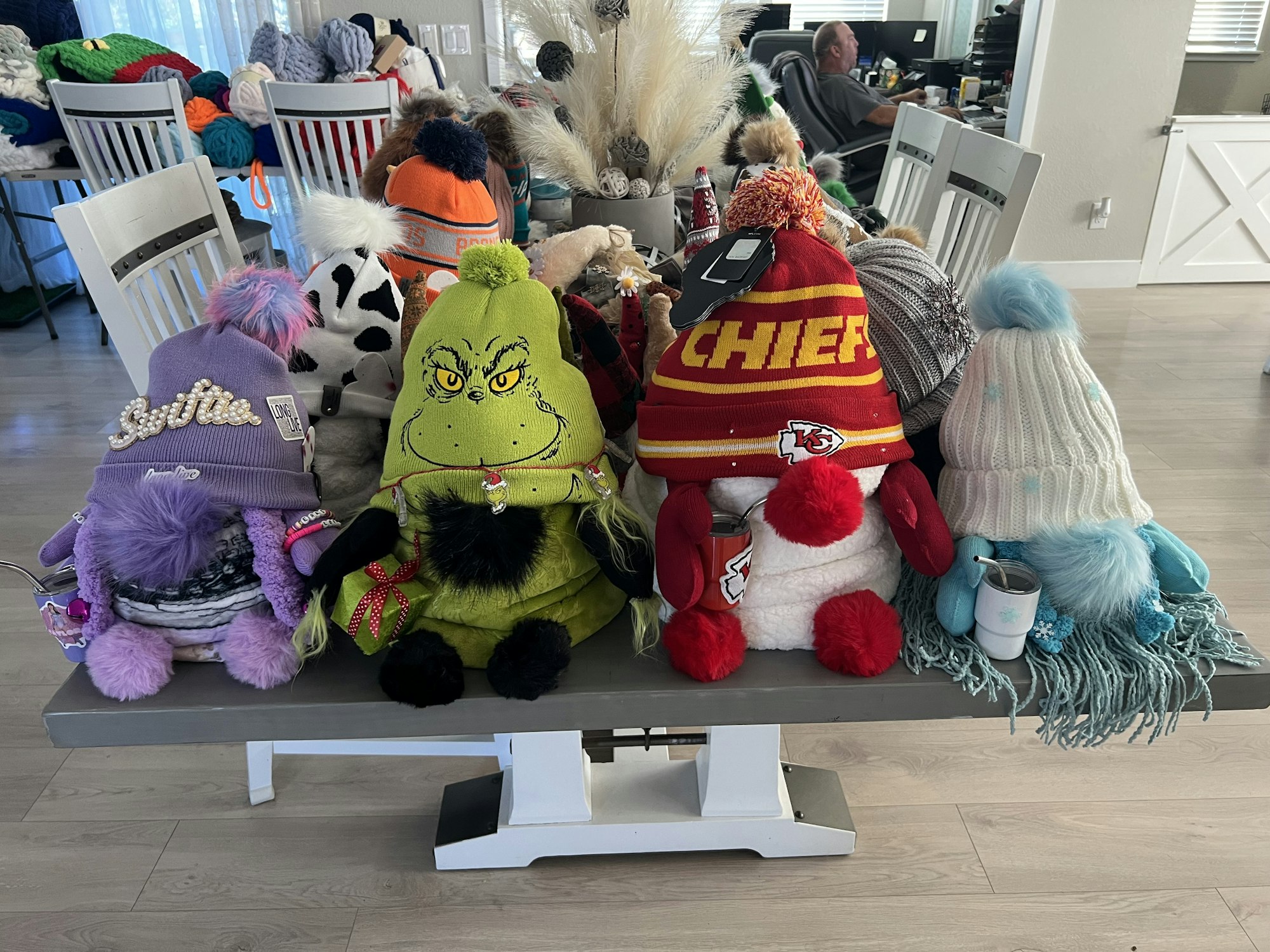 A row of whimsical gnomes wearing festive hats and scarves is lined up on a table.