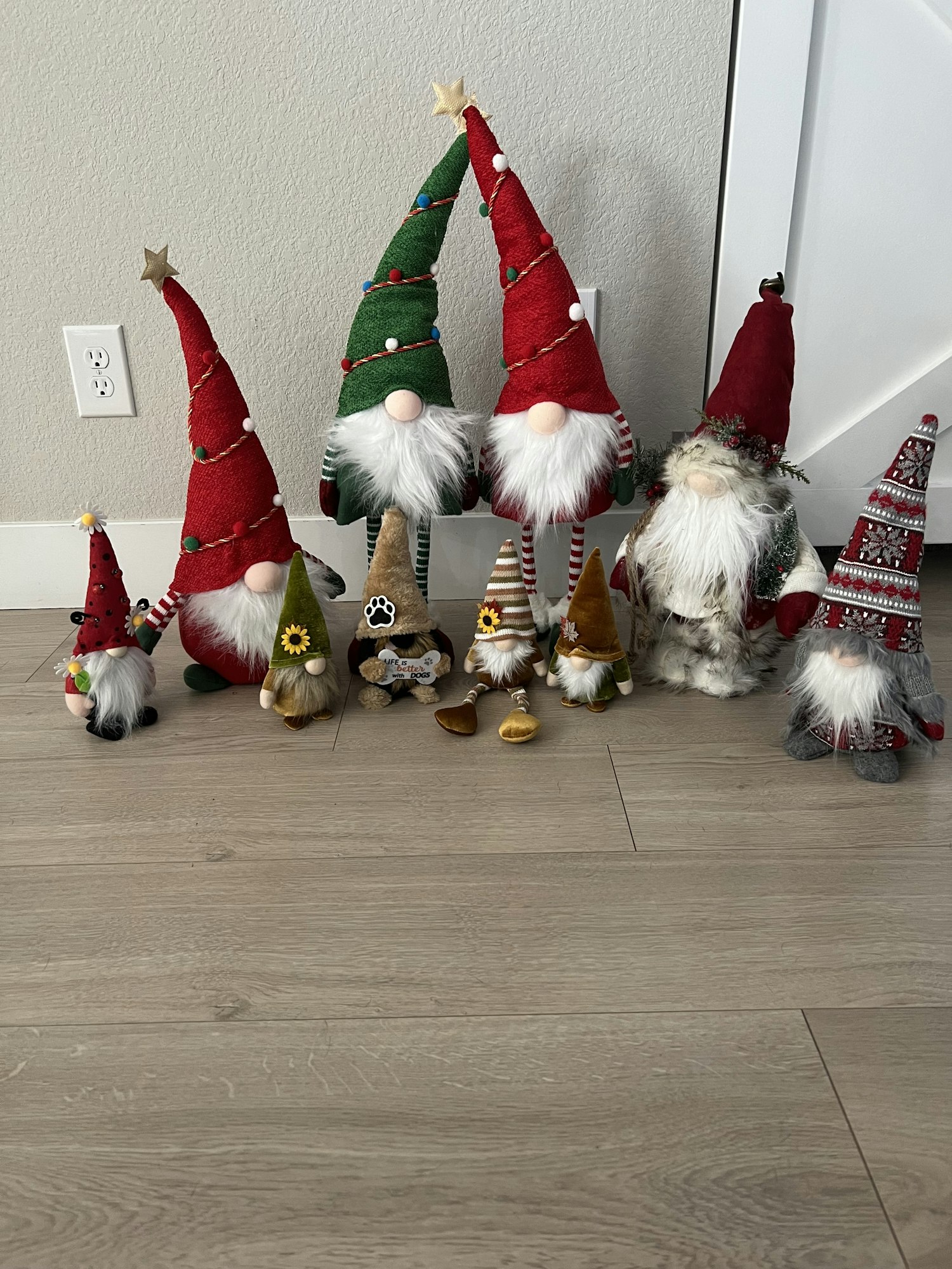 A group of decorative Scandinavian-style gnomes with tall hats, beards, and festive colors, arranged on a wooden floor.