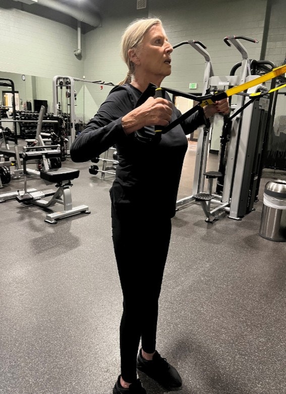 A women working out with TRX suspension straps in a gym.