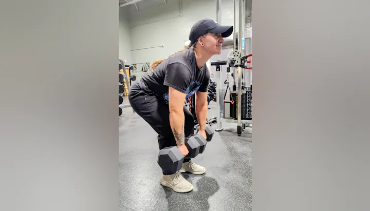 A person is lifting dumbbells in a gym, demonstrating a strength training exercise.