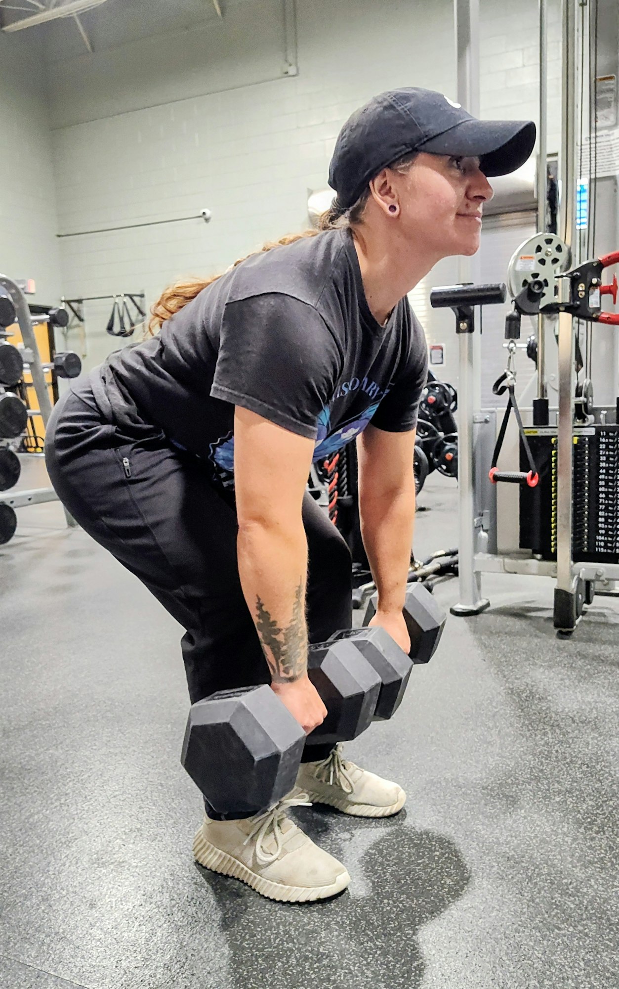 A person is lifting dumbbells in a gym, demonstrating a strength training exercise.