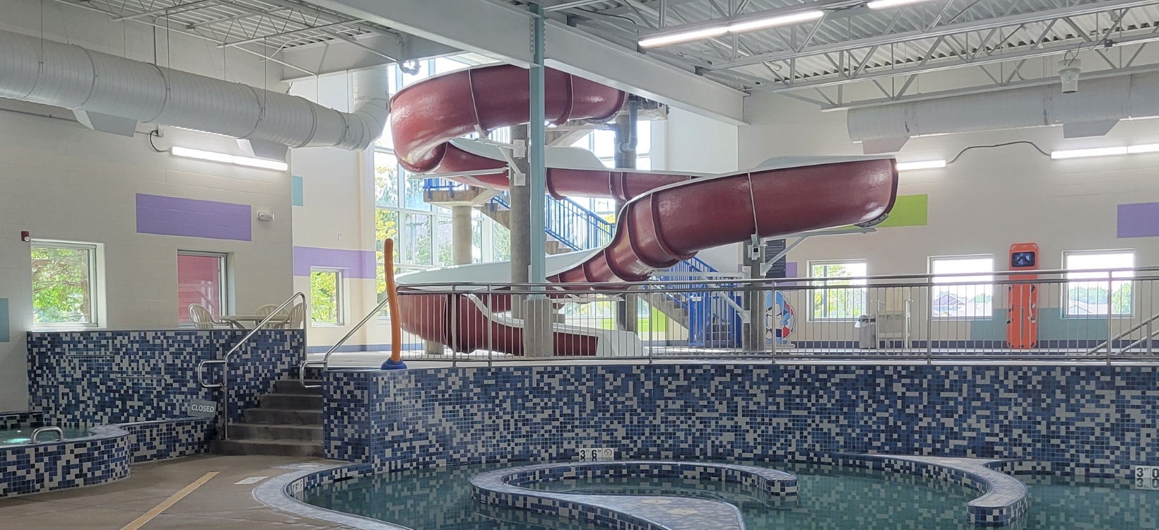 Indoor pool with a waterslide and a hot tub.