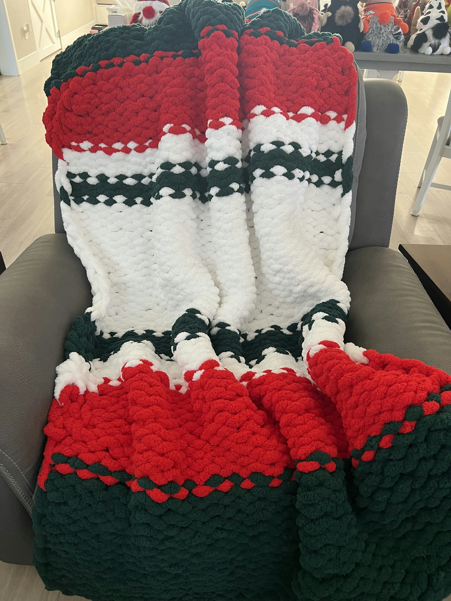 A cozy knit blanket with red, white, and green patterns draped over a sofa.