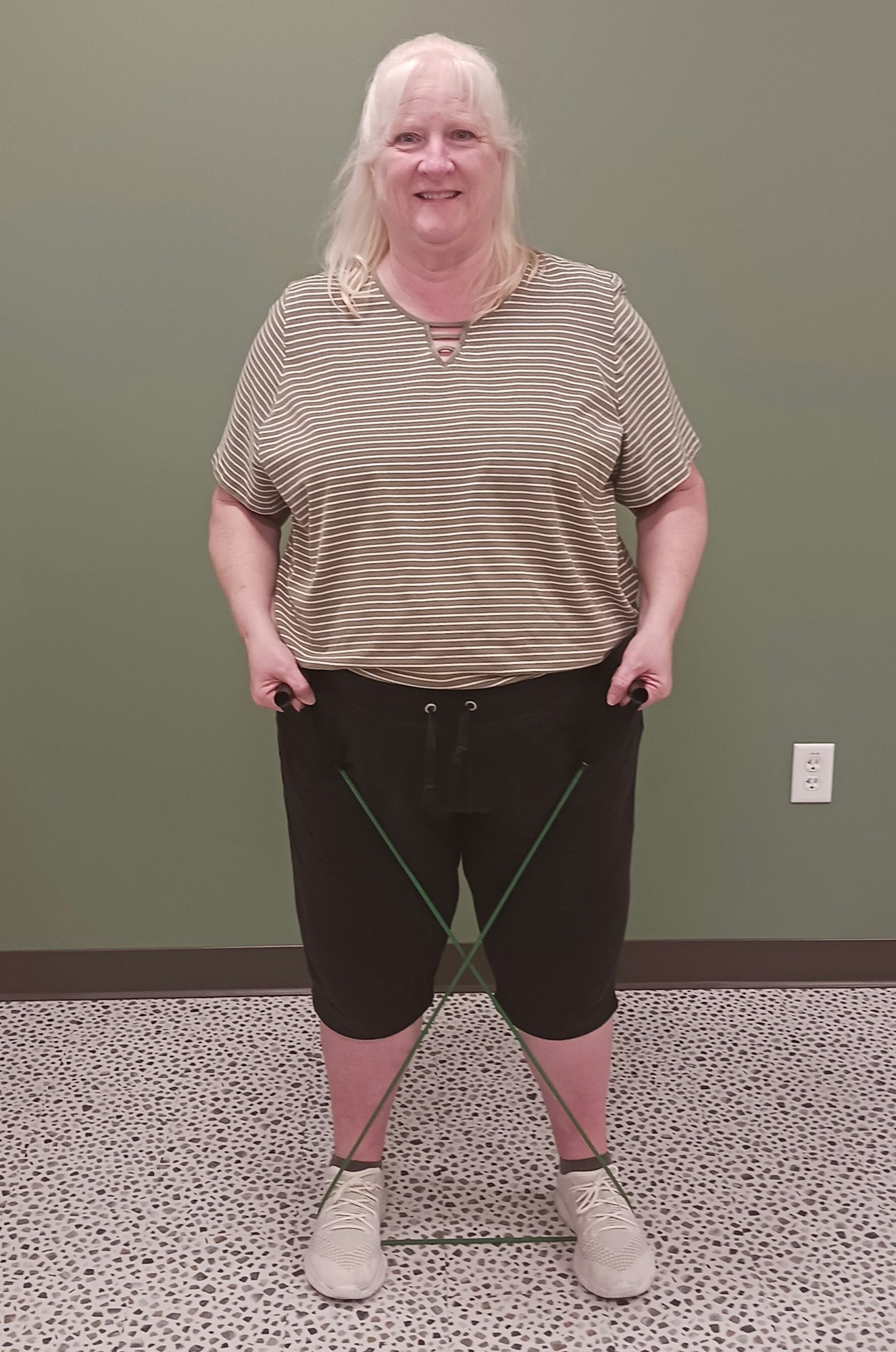 A person standing with an exercise resistance band around their ankles.