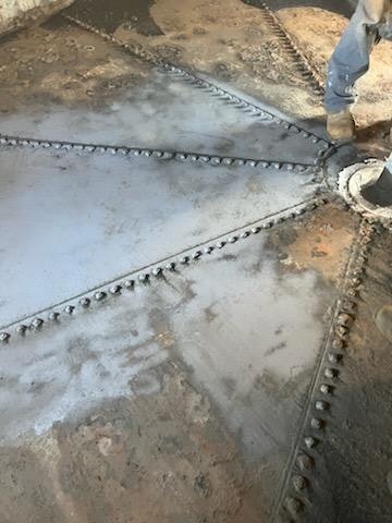 Metal plate with rivets and a person's leg in workwear.