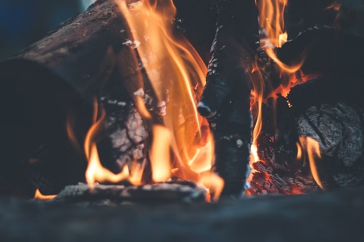 Burning logs with bright orange flames and charred wood.