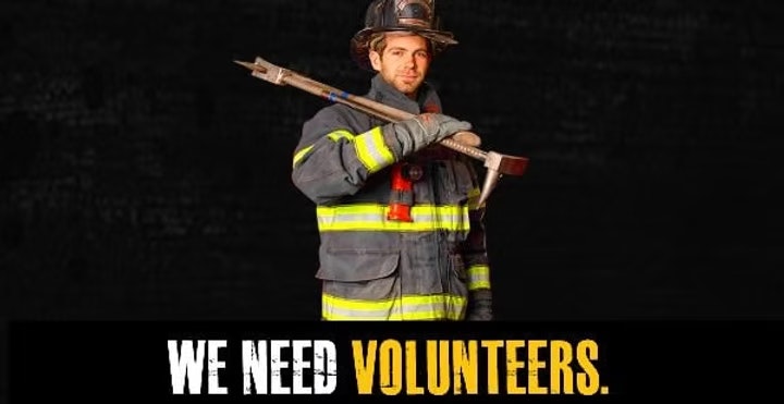 A firefighter holding an axe, with the text "We Need Volunteers."